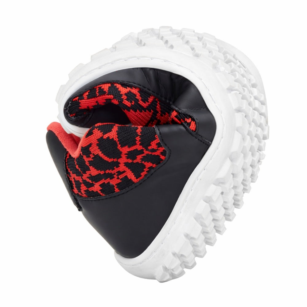 Der QASEY Red Sneaker von ZAQQ ist in der Mitte gebogen, wodurch die flexible Kautschuksohle hervorgehoben und das rot-schwarze Meshgewebe auf dem Obermaterial zur Schau gestellt wird. Die graue Sohle mit ihrer rauen Textur betont die Flexibilität und den Halt des Schuhs.