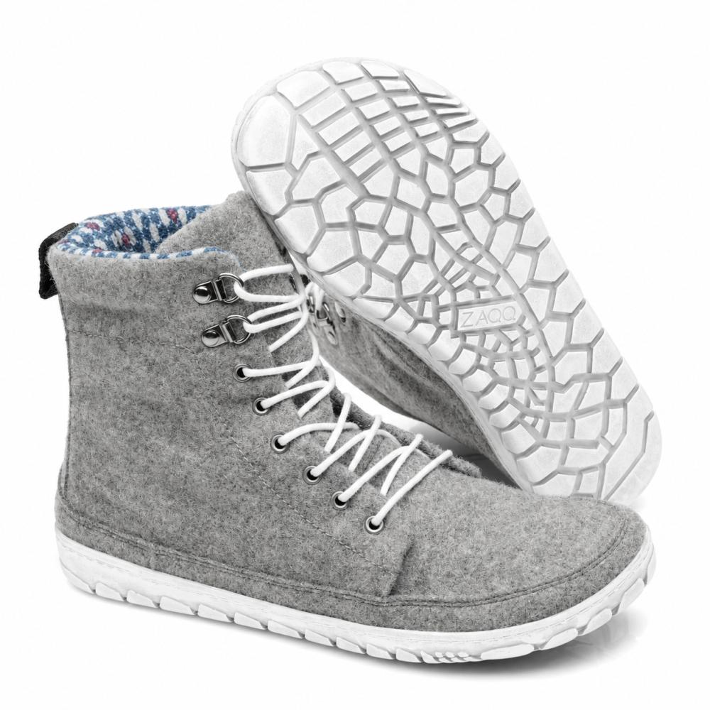 Vystaven je pár QICE Grey High-Top tenisek od ZAQQ s bílými tkaničkami. Jedna bota stojí vzpřímeně, zatímco druhá je nakloněná, aby zdůraznila strukturovanou, vzorovanou outdoorovou podrážku.