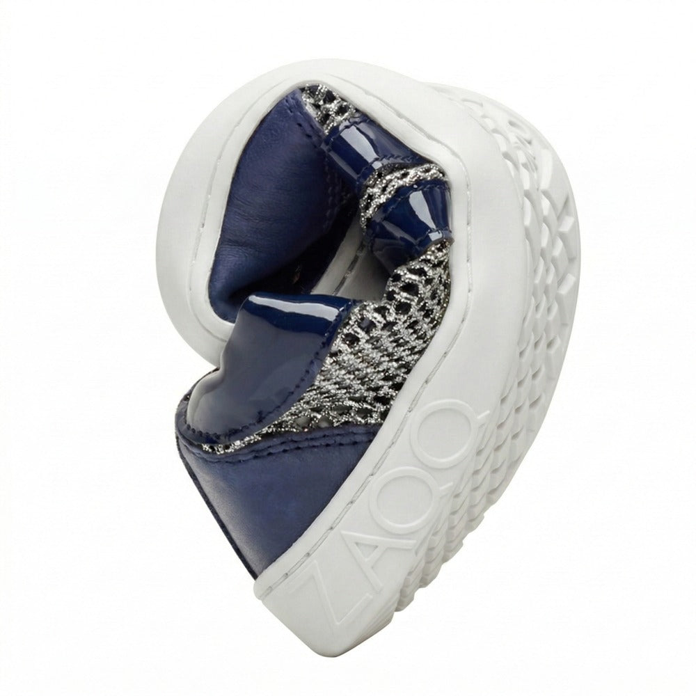 Der QIMBERLY Blue von ZAQQ ist zu einer Kugel zusammengerollt, um seine Flexibilität zu demonstrieren. Dieser Barfuß-Sneaker, erhältlich in Marineblau und Silber, ist aus hochwertigem Nappaleder gefertigt und verfügt über ein strukturiertes Muster auf der Sohle, auf dessen Seite der Markenname von ZAQQ prominent angebracht ist.