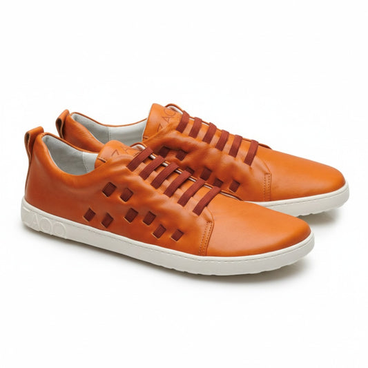 Wir präsentieren den STRAQ Sierra von ZAQQ: ein Paar stylische orangefarbene Sneaker aus Nappaleder mit weißer Sohle. Die Seiten sind mit quadratischen Ausschnittmustern versehen und der Markenname ZAQQ ist elegant auf der Ferse eingeprägt. Diese Barfuß-Sneaker zeichnen sich durch ein Schnürdesign mit braunen Schnürsenkeln aus.