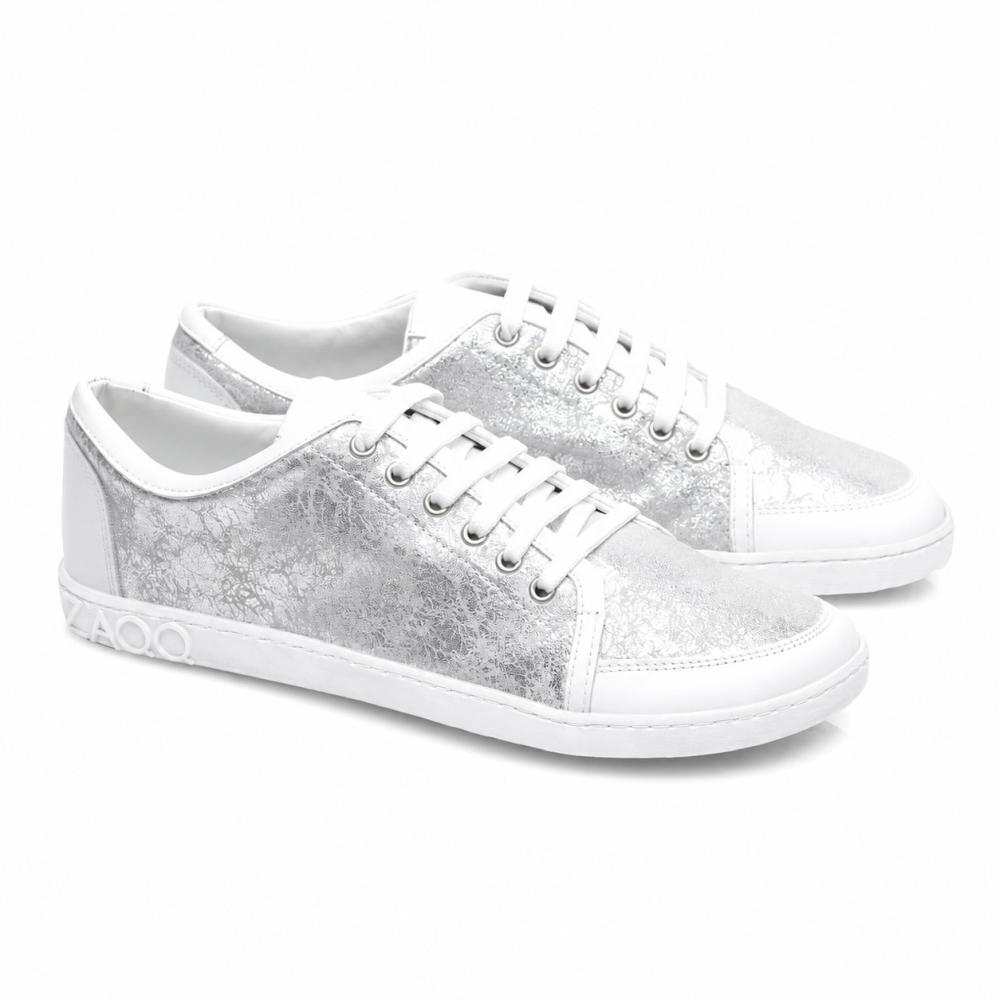 Představujeme TIQQ Silver White od ZAQQ: Stylové tenisky z vysoce kvalitní nappa kůže s nápadnou metalickou stříbrnou texturou a bílými podrážkami. Tyto tenisky jsou vybaveny zářivě bílými tkaničkami, ozdobným šitím a výrazným detailem 4000 na boku podrážky.